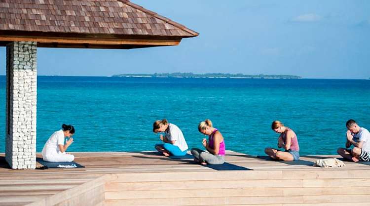 Yoga e massaggi ayurvedici su una spiaggia da sogno di un atollo